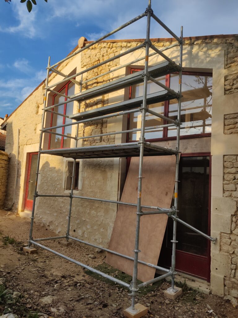 alt="Application de l’enduit lors du ravalement façade pierre vue"