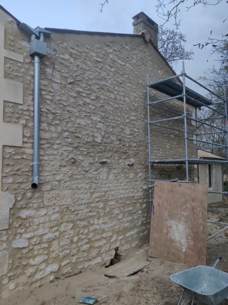 alt="Application de l’enduit lors du ravalement façade pierre vue"